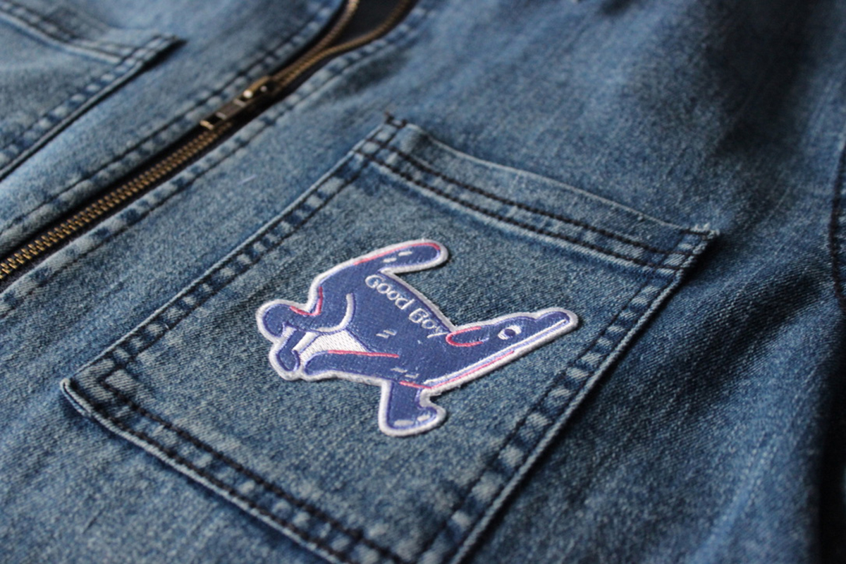 Photograph of Jean jacket with blue illustrated dog patch, text on patch says good boy