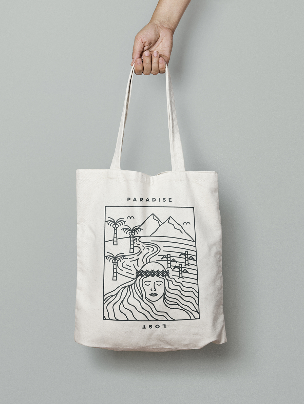 A portion of 'Paradise Lost' artwork printed on natural colored tote bag in black, shows woman in front of natural landscape with shoreline, palm trees, and mountains.
