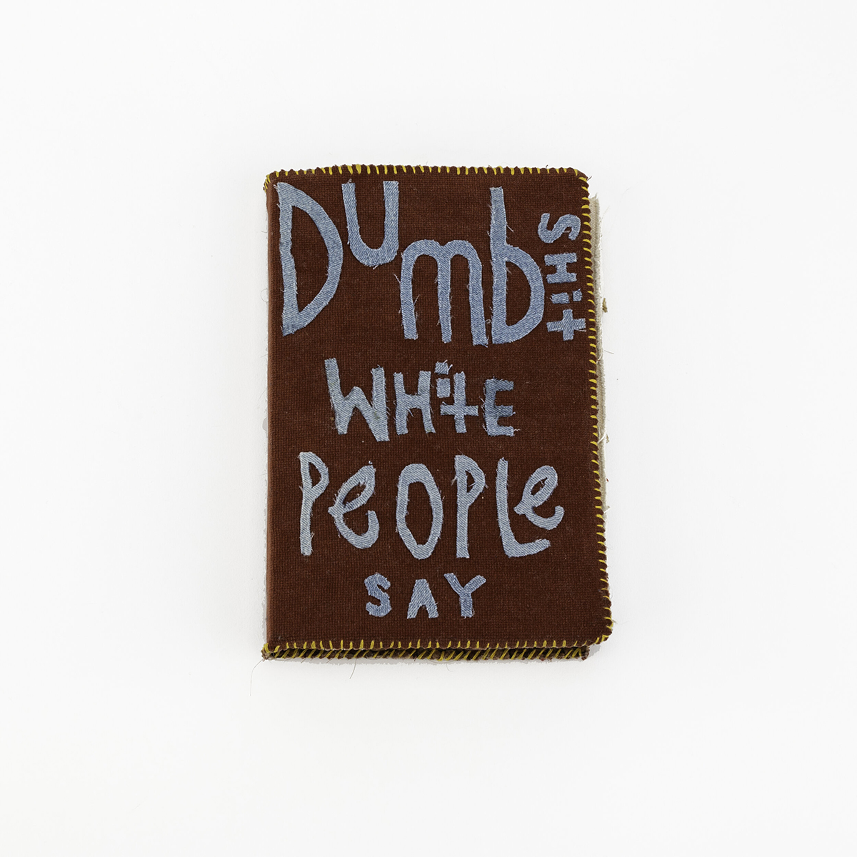 Handbound book with stitched binding and fabric scrap lettering, text reads, 'Dumb shit white people say'